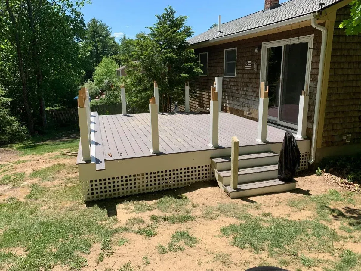 A wooden deck with stairs is in front of a house.