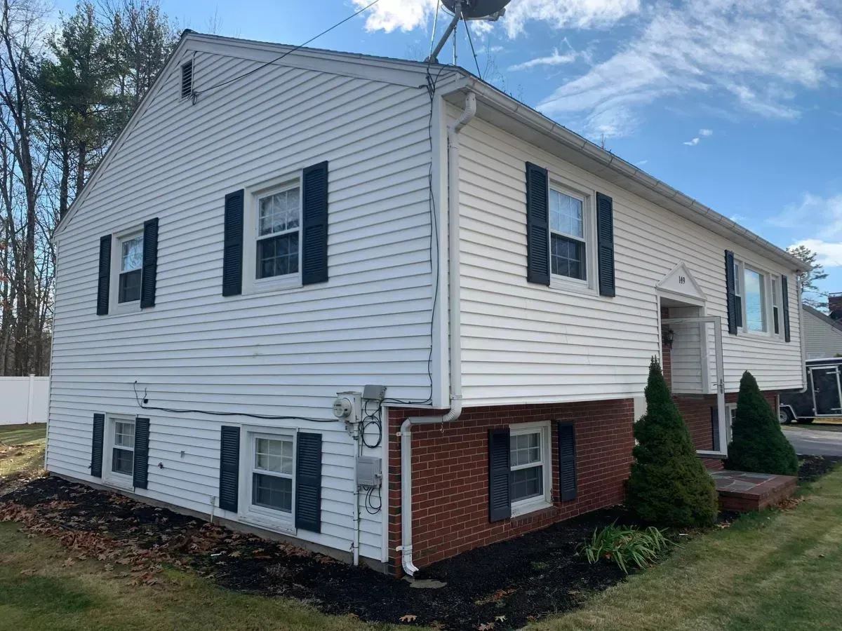 A white house with black shutters and a satellite dish on top of it.