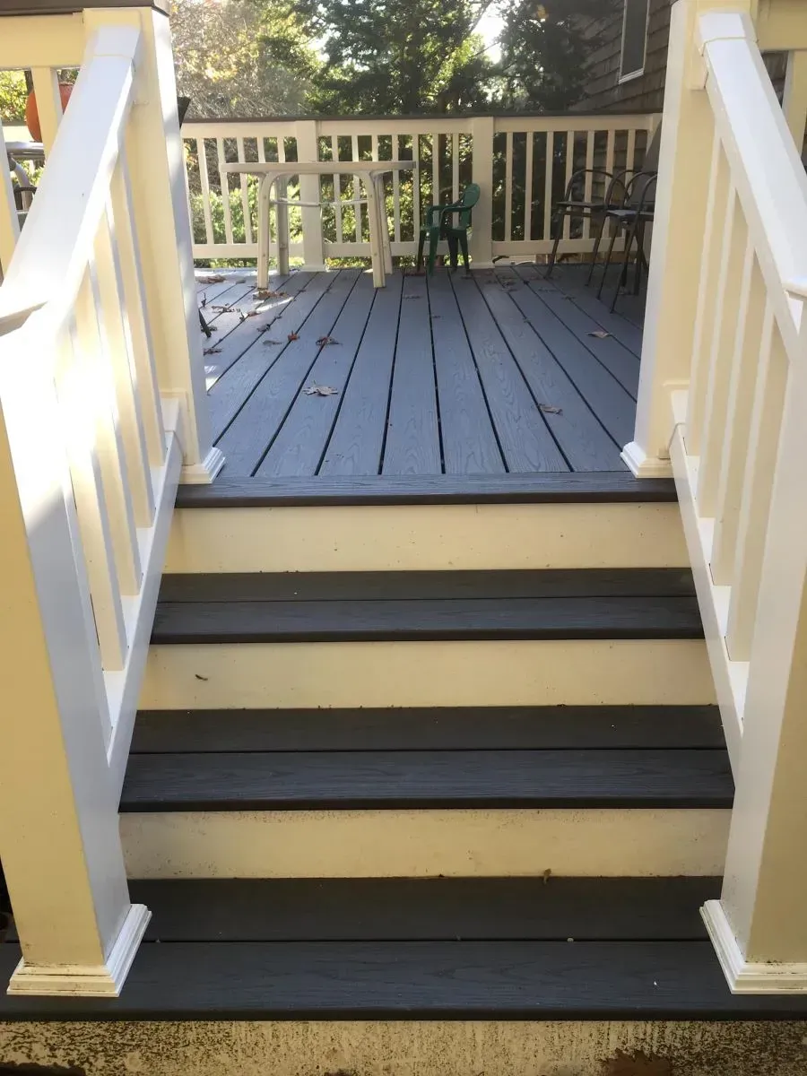 A deck with stairs leading up to it and a white railing
