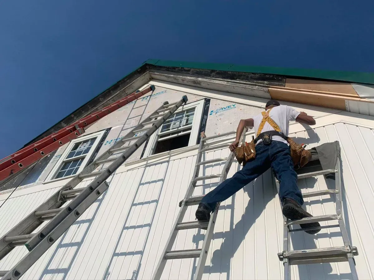 A man is climbing a ladder on the side of a building