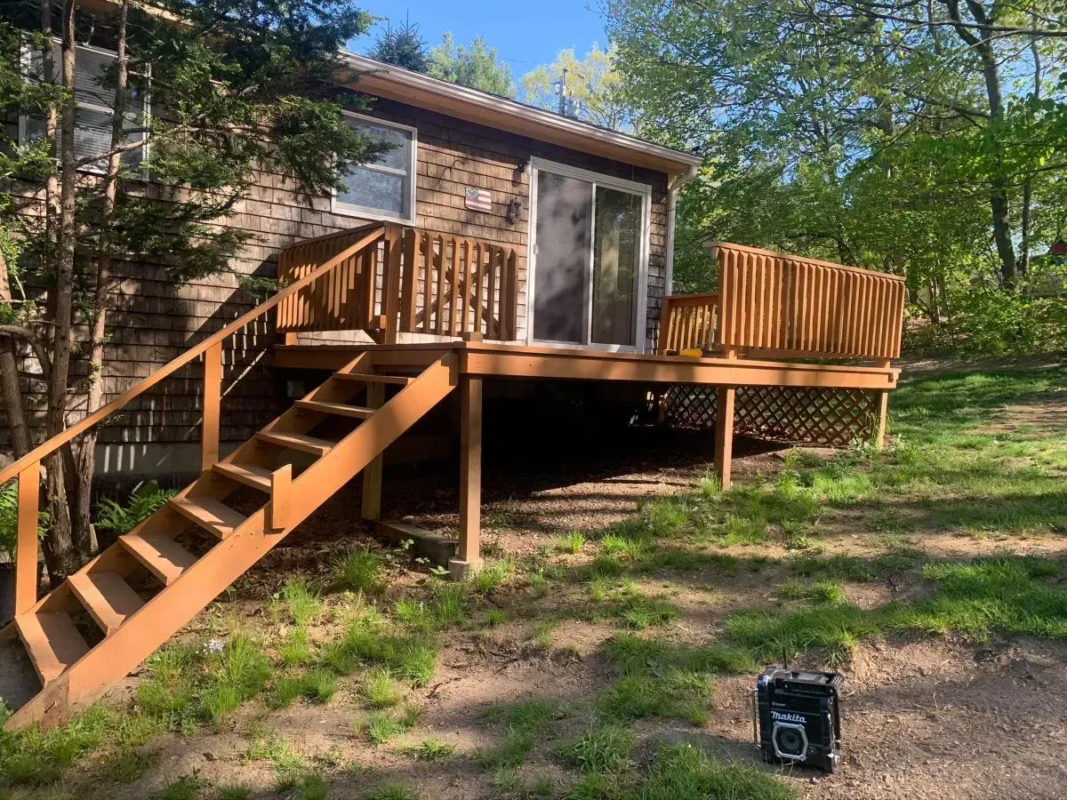 A house with a wooden deck and stairs in front of it.