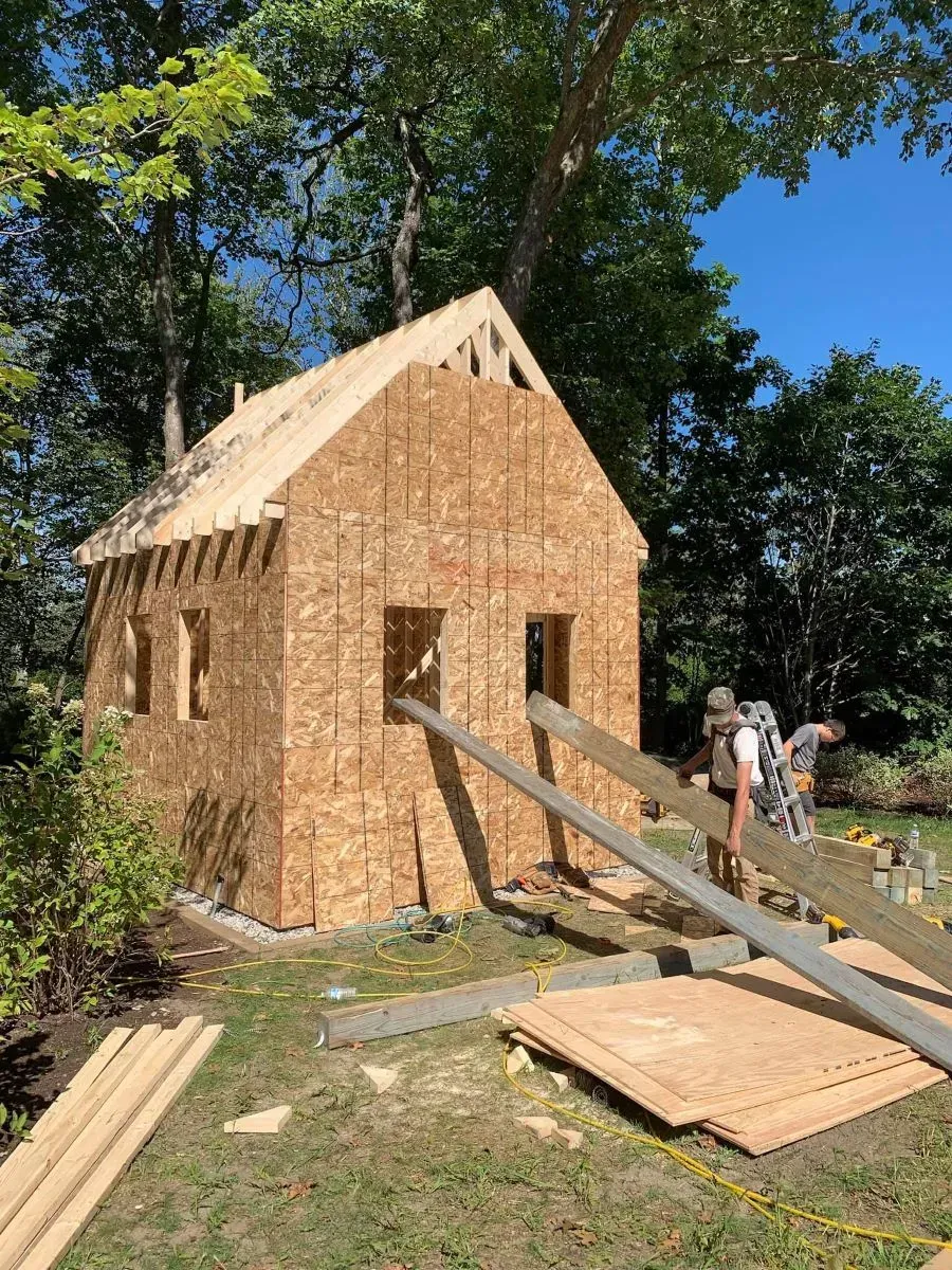 A wooden house is being built in a backyard.