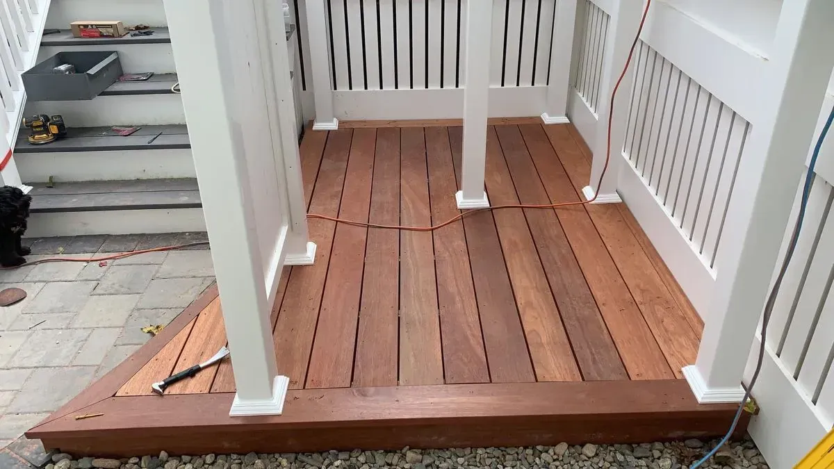 A wooden deck with a white railing is being built.