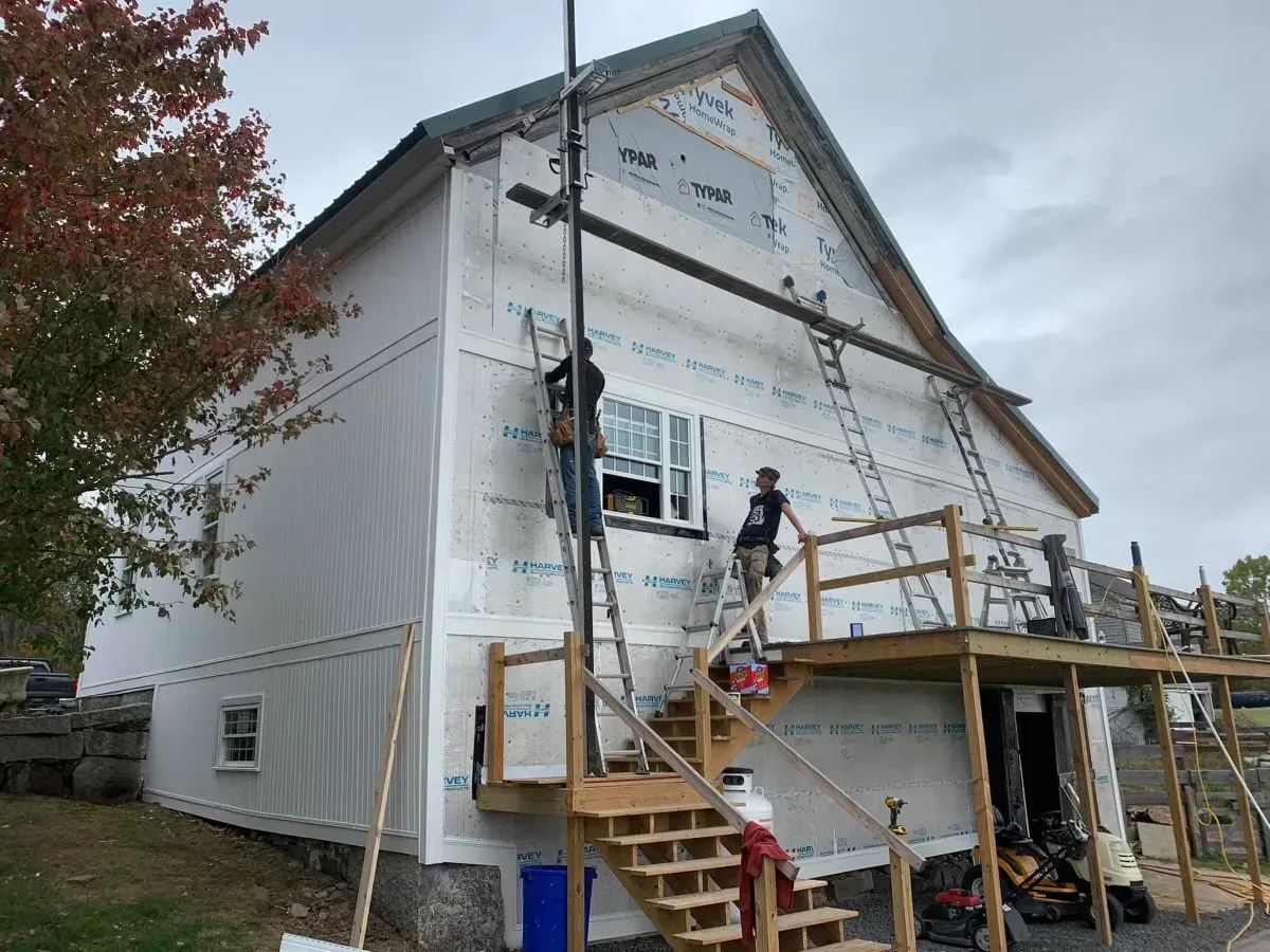A group of people are working on the side of a house.