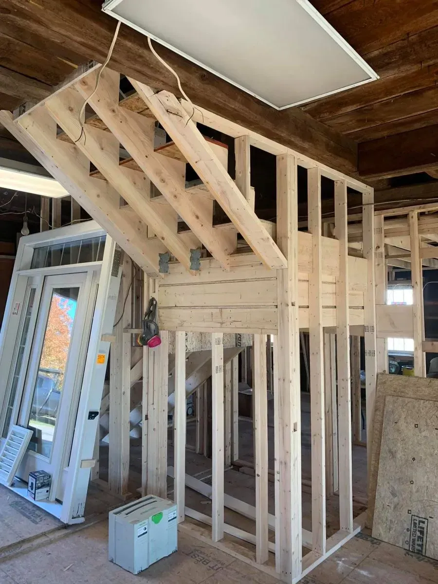 A wooden staircase is being built in a building under construction.