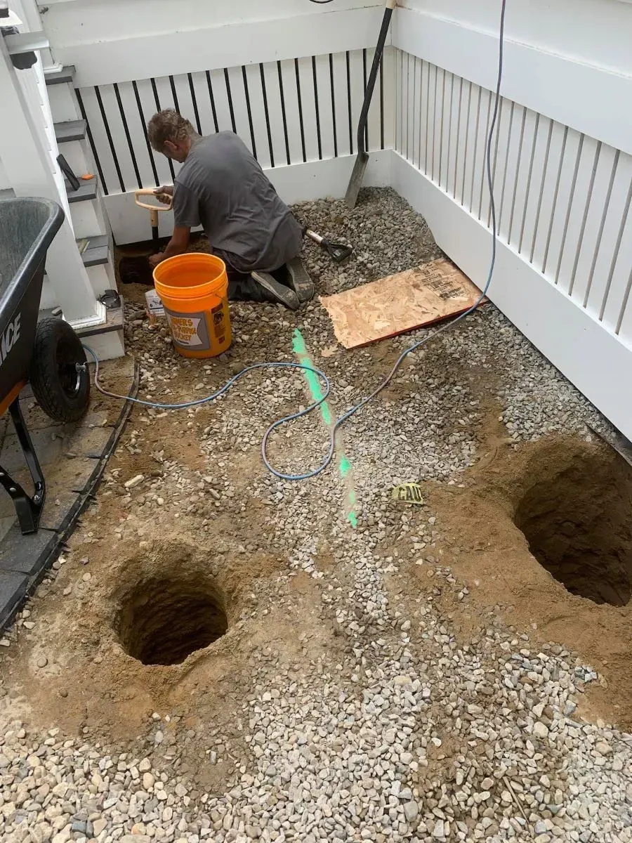A man is kneeling on the ground digging holes in the ground.