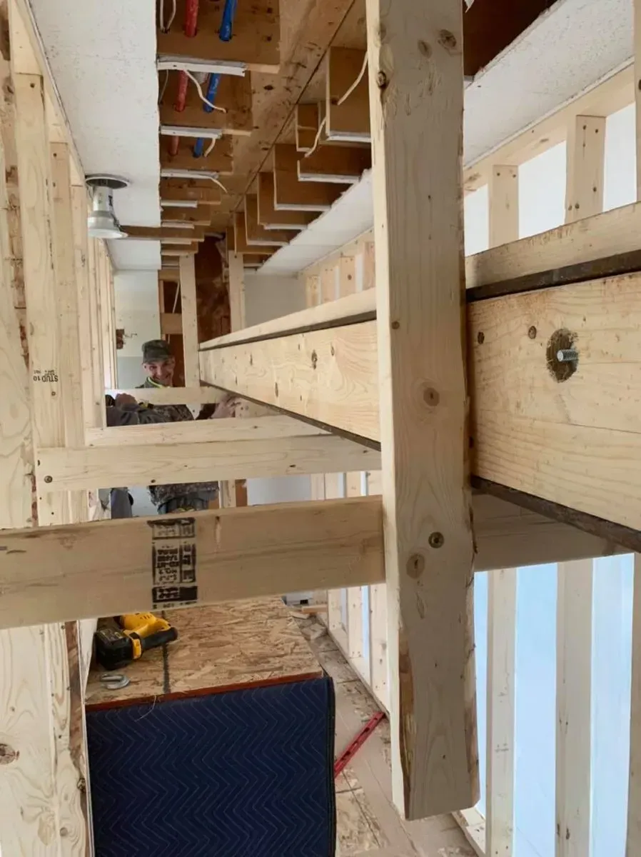 A man is working on a wooden structure in a room.