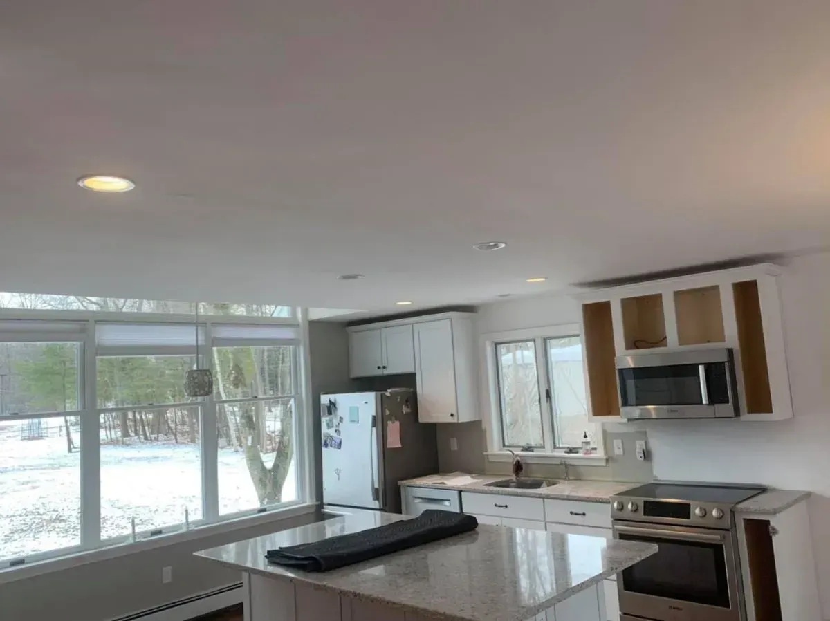 A kitchen with white cabinets , stainless steel appliances , and a large island.