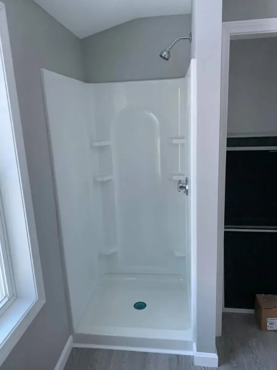 A bathroom with a walk in shower and a window.