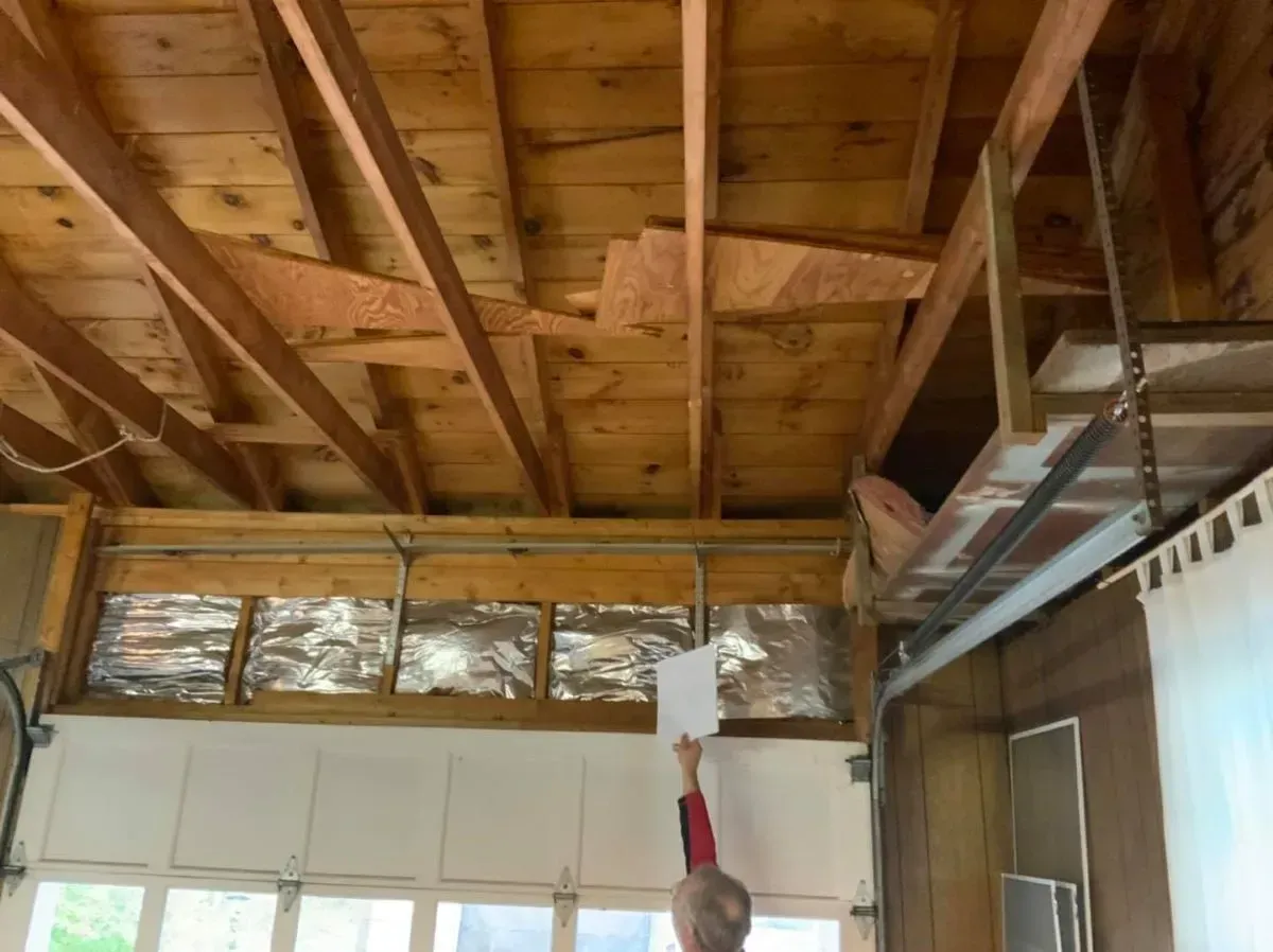 A man is holding a piece of paper in a room with a wooden ceiling.