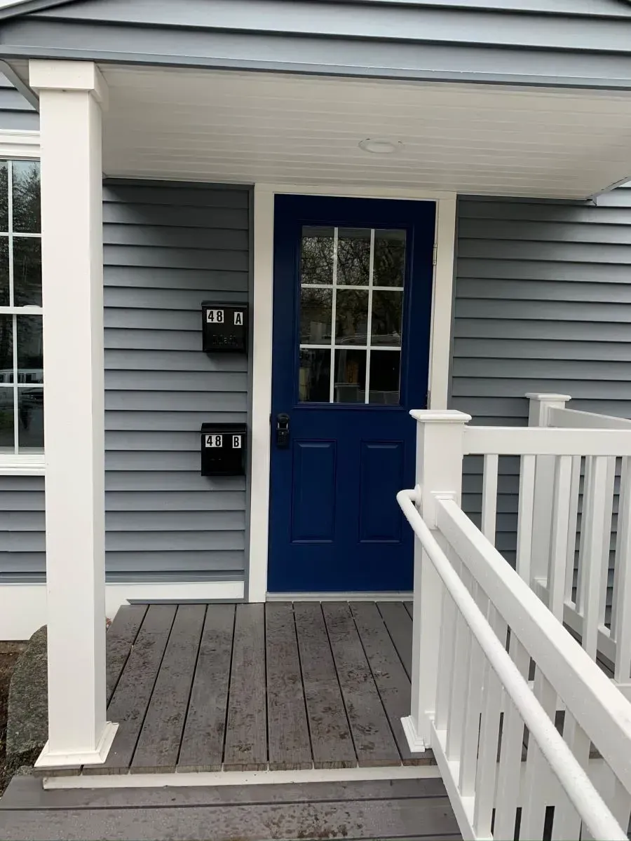 A blue door on a house with a white railing