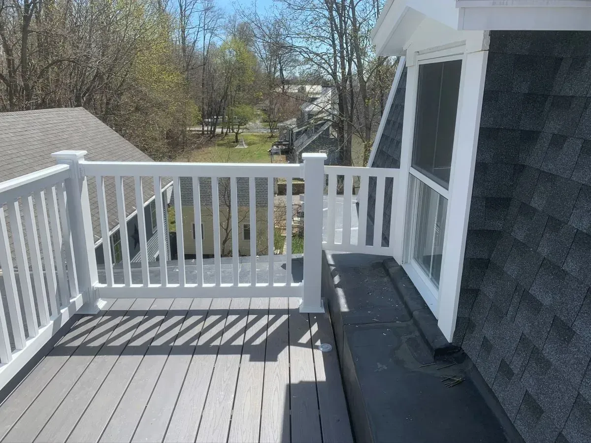 A deck with a white railing and a screened in window