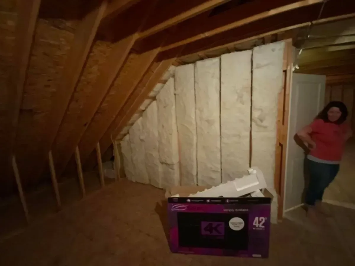 A woman is standing in an attic next to a box that says 42
