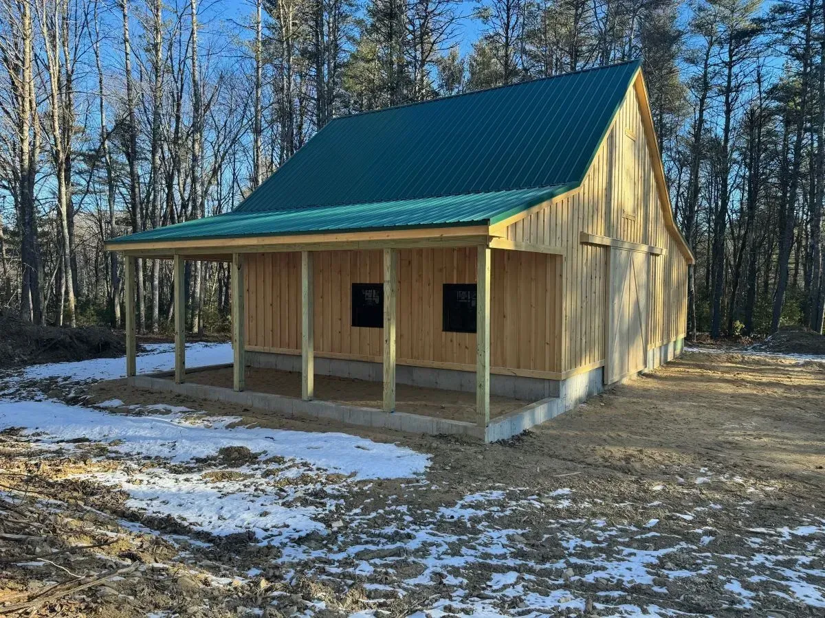 A small wooden house with a green roof and a porch.