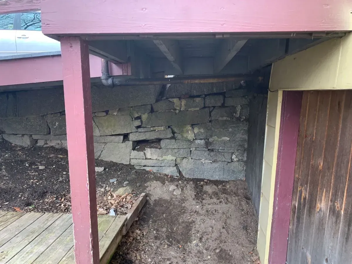 A wooden deck with a stone wall behind it