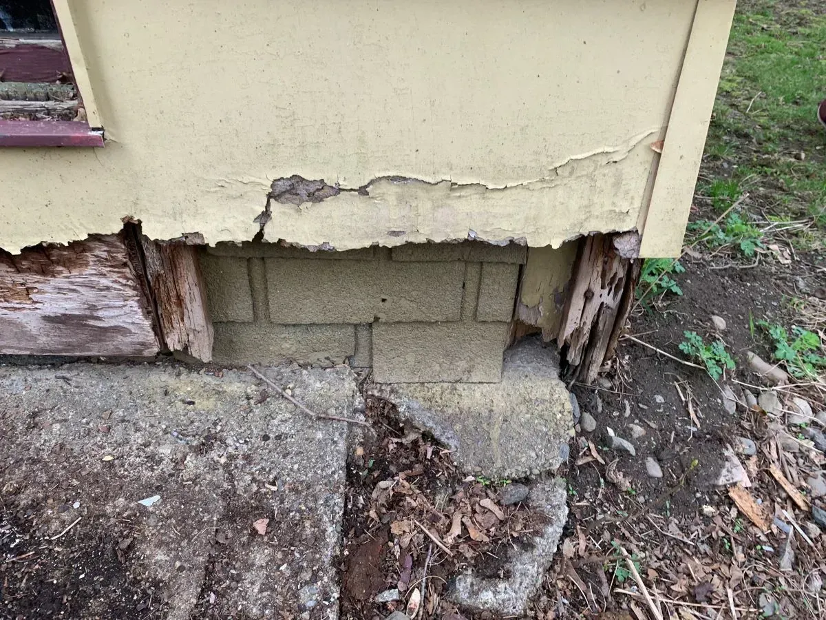 A close up of a house with a hole in the ground.