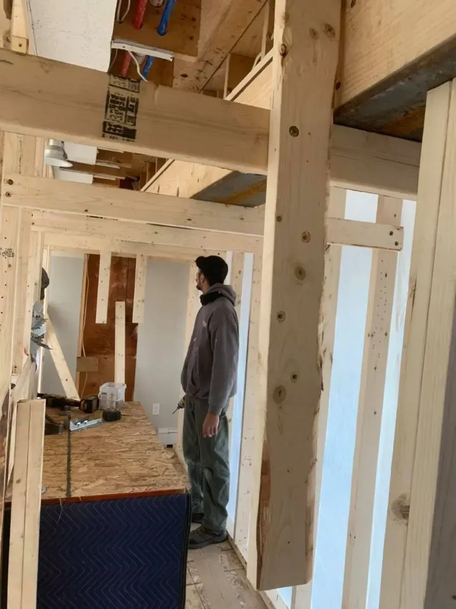 A man is standing in a room with wooden beams.