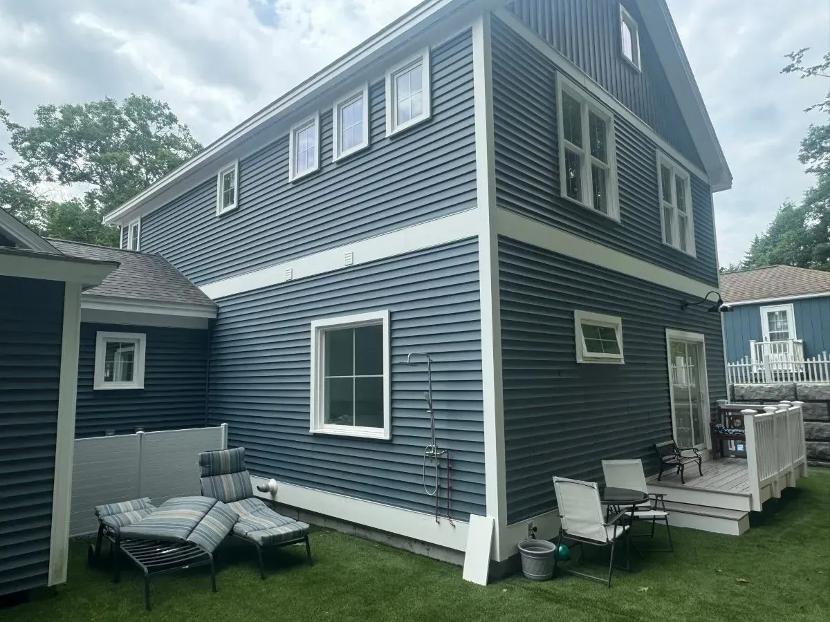 A large blue house with a lot of windows is sitting on top of a lush green lawn.