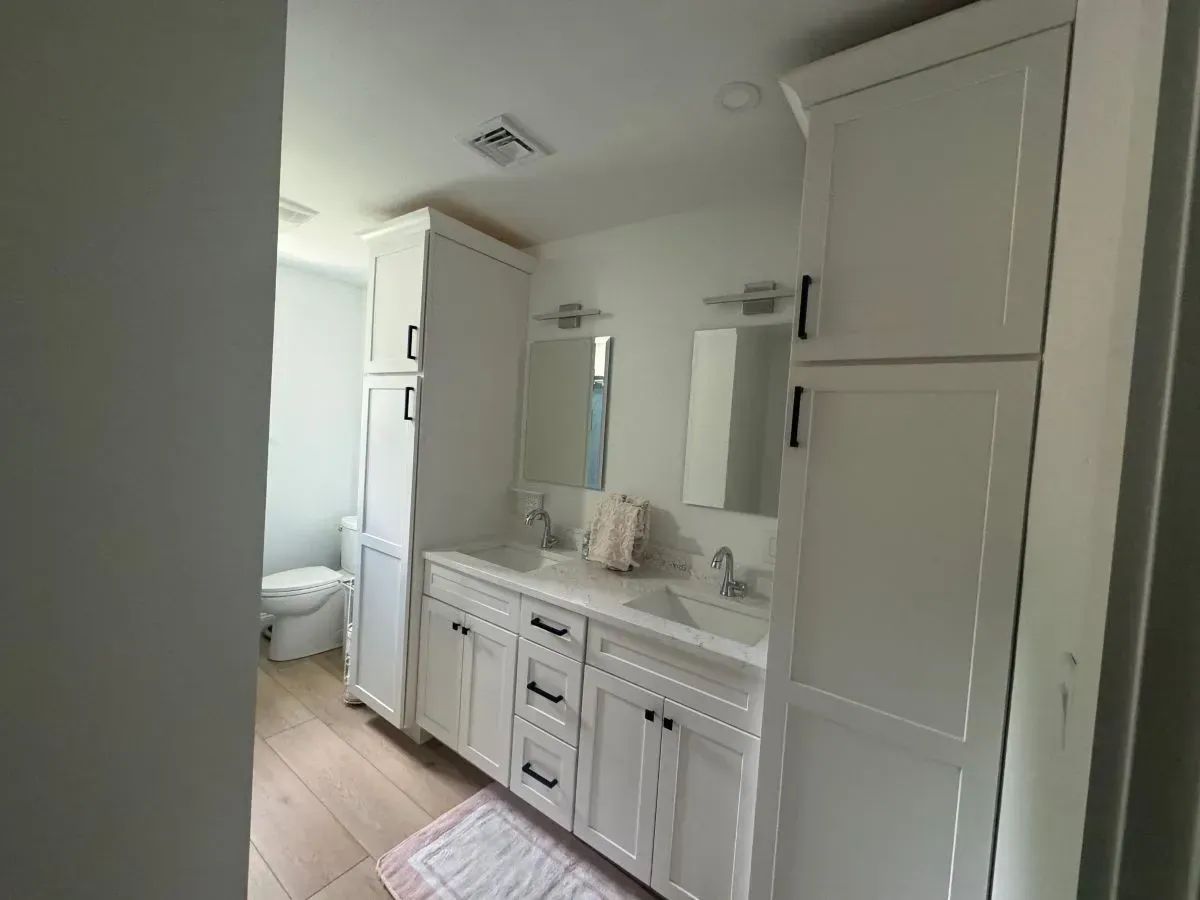 A bathroom with two sinks , two mirrors and a toilet.