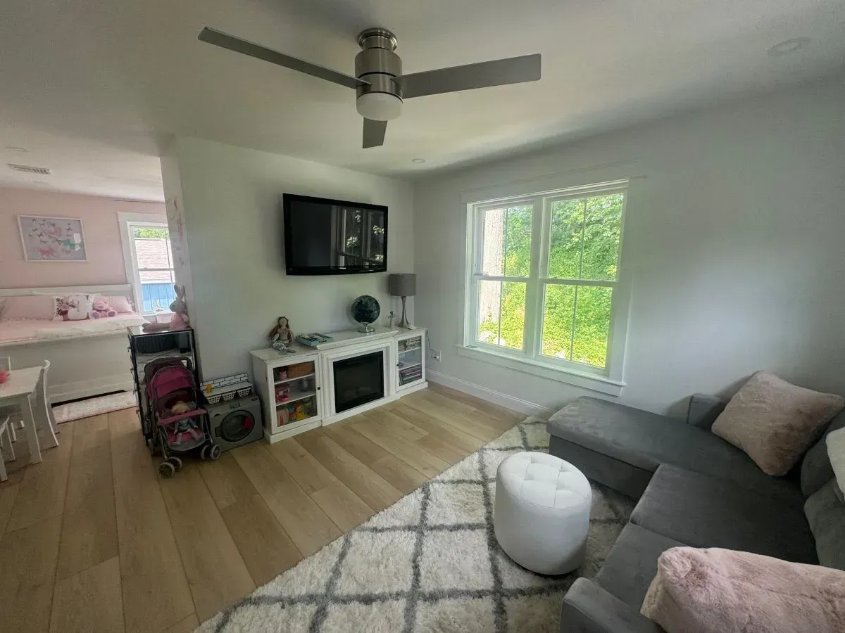 A living room with a couch , fireplace , television and ceiling fan.