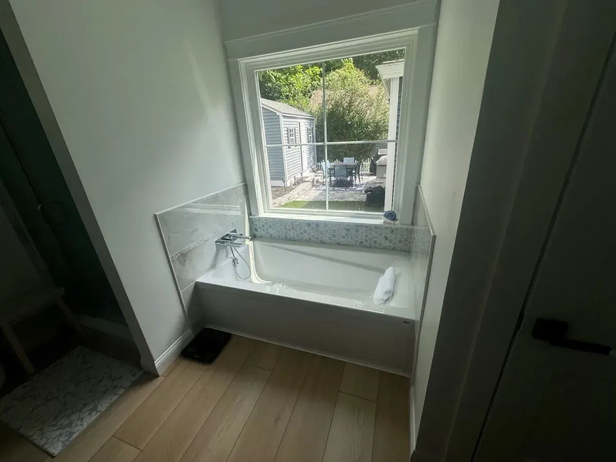 A bathroom with a bathtub and a window.