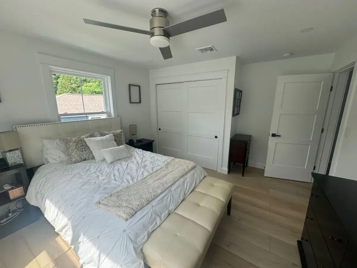 A bedroom with a bed and a ceiling fan.