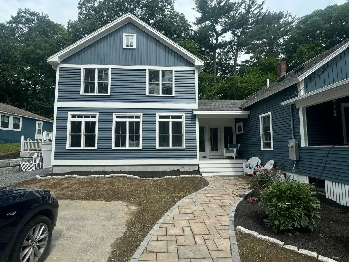 A blue and white house with a car parked in front of it.