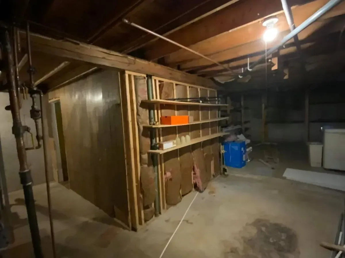 A basement with shelves and a blue box on the floor.