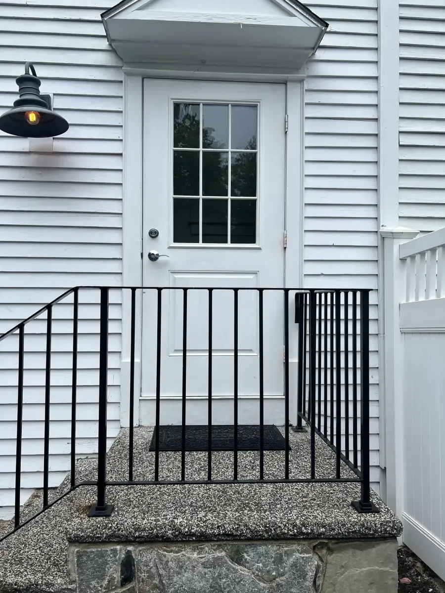 A white house with a black railing and stairs