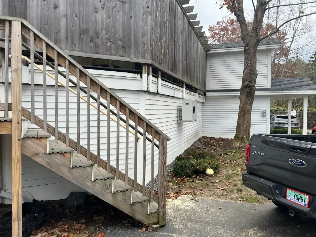 A truck is parked in front of a house with stairs leading up to it.