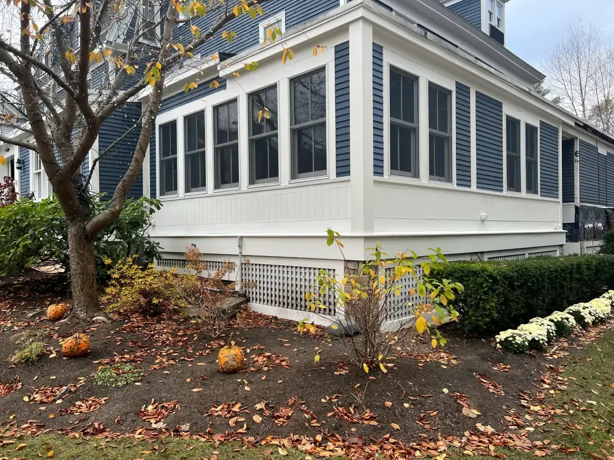 A house with a screened in porch and pumpkins in front of it.