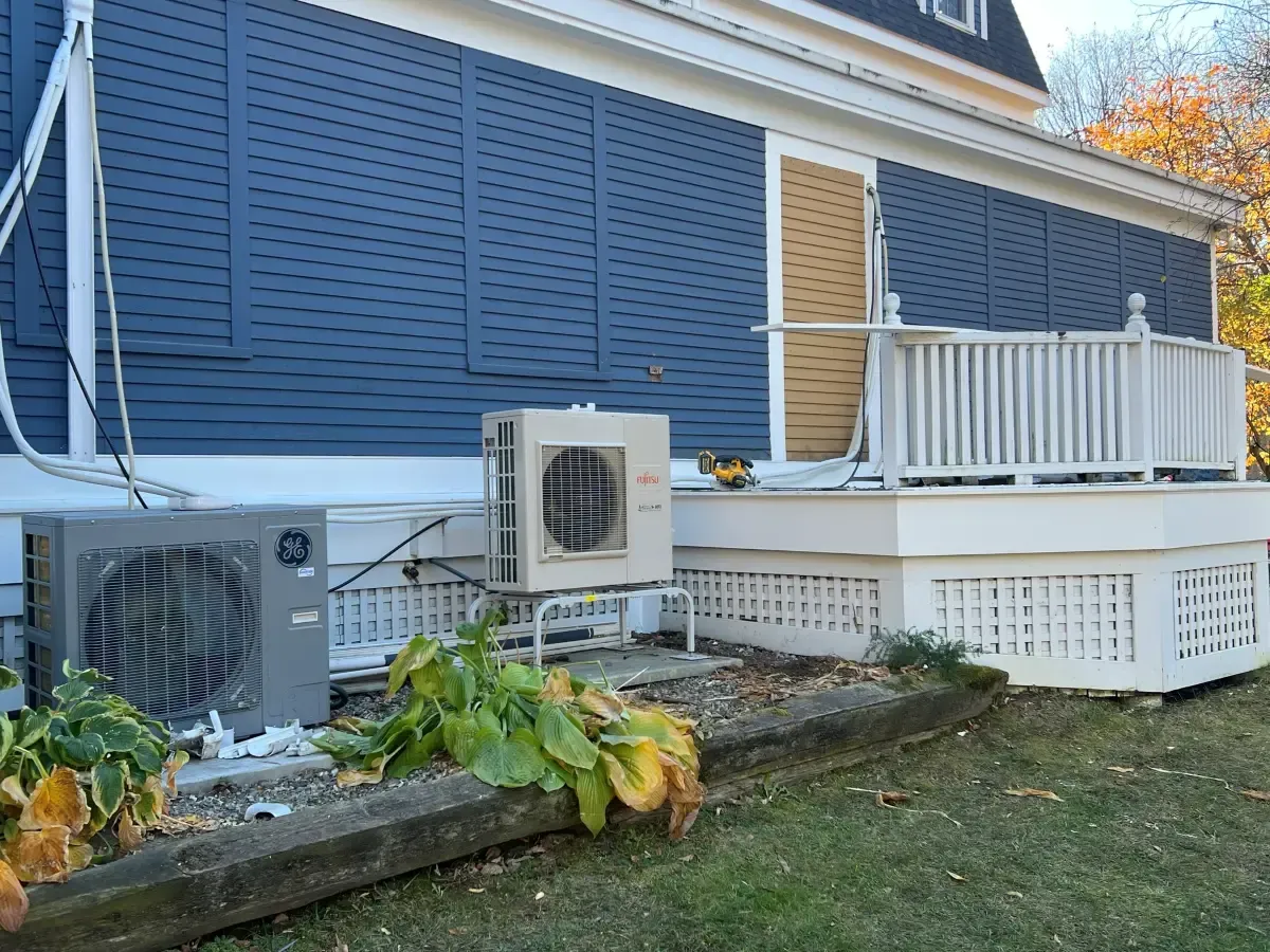 There are two air conditioners on the side of a house.