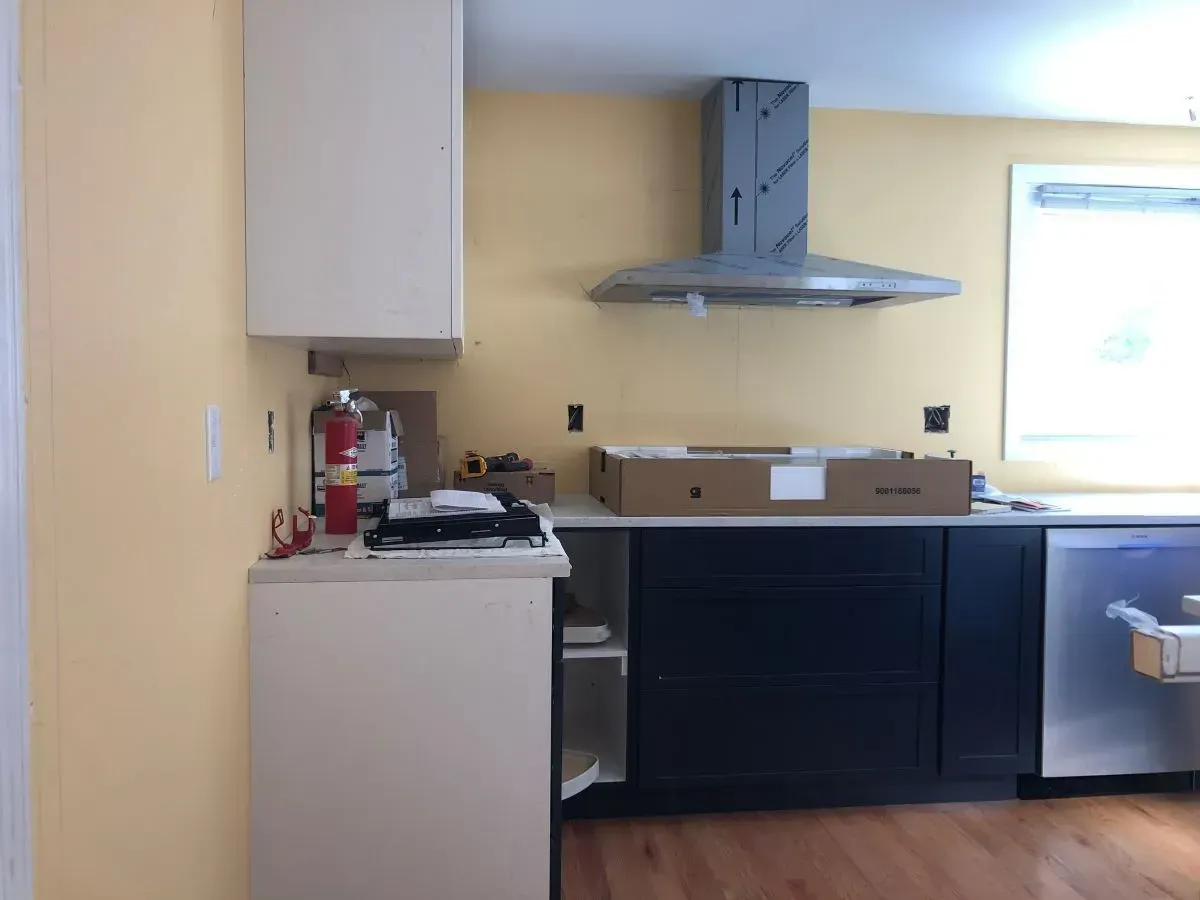 A kitchen with yellow walls and black cabinets is being remodeled