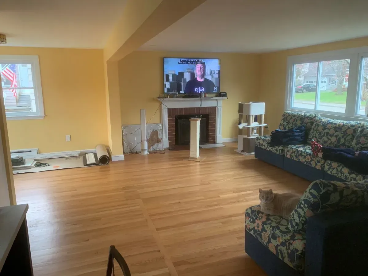 A living room with a couch , chair , television and fireplace.