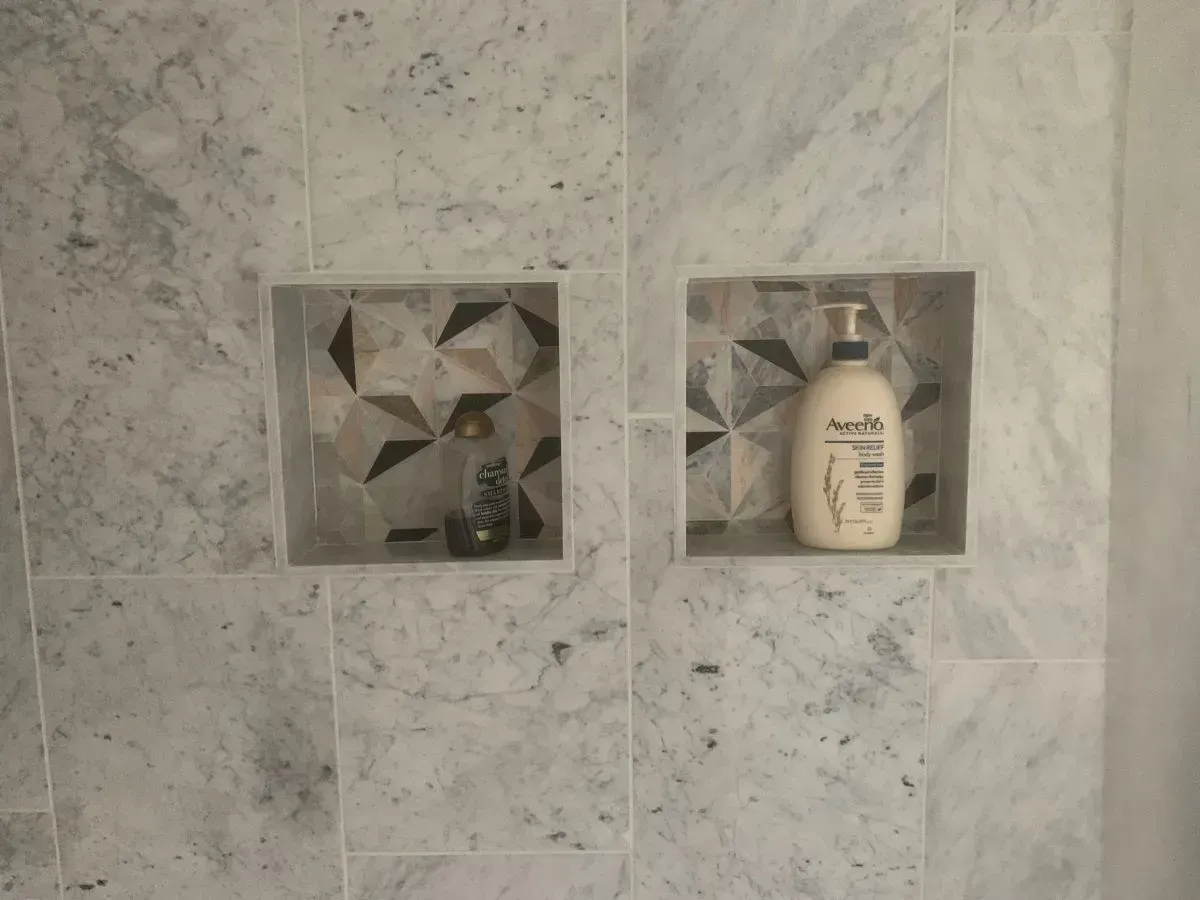 A bottle of lotion is sitting in a shower niche.