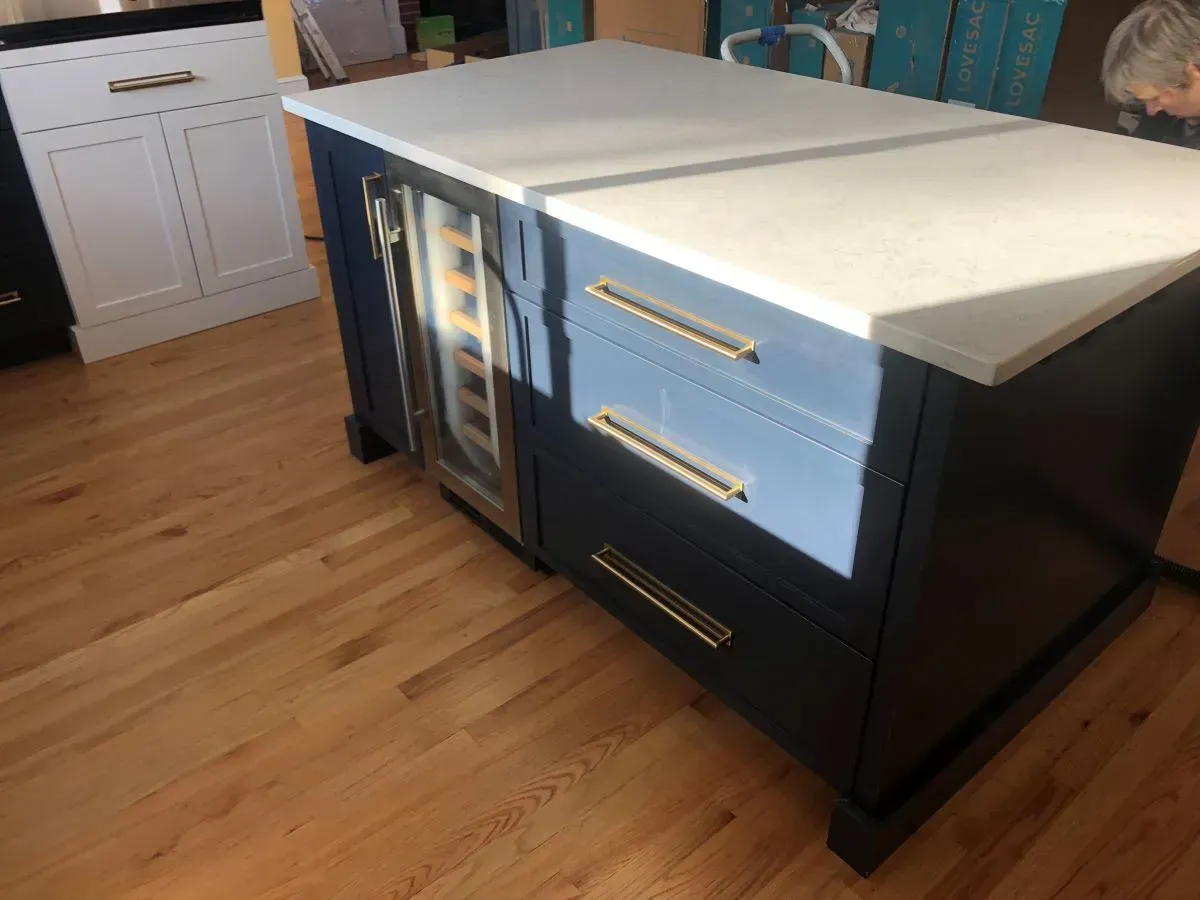 A kitchen island with drawers and a wine cooler.