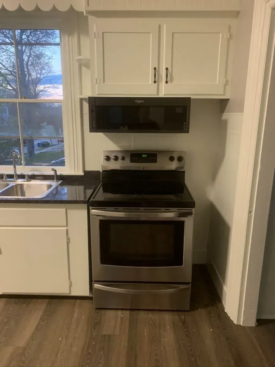 A kitchen with a stove , sink , and microwave.