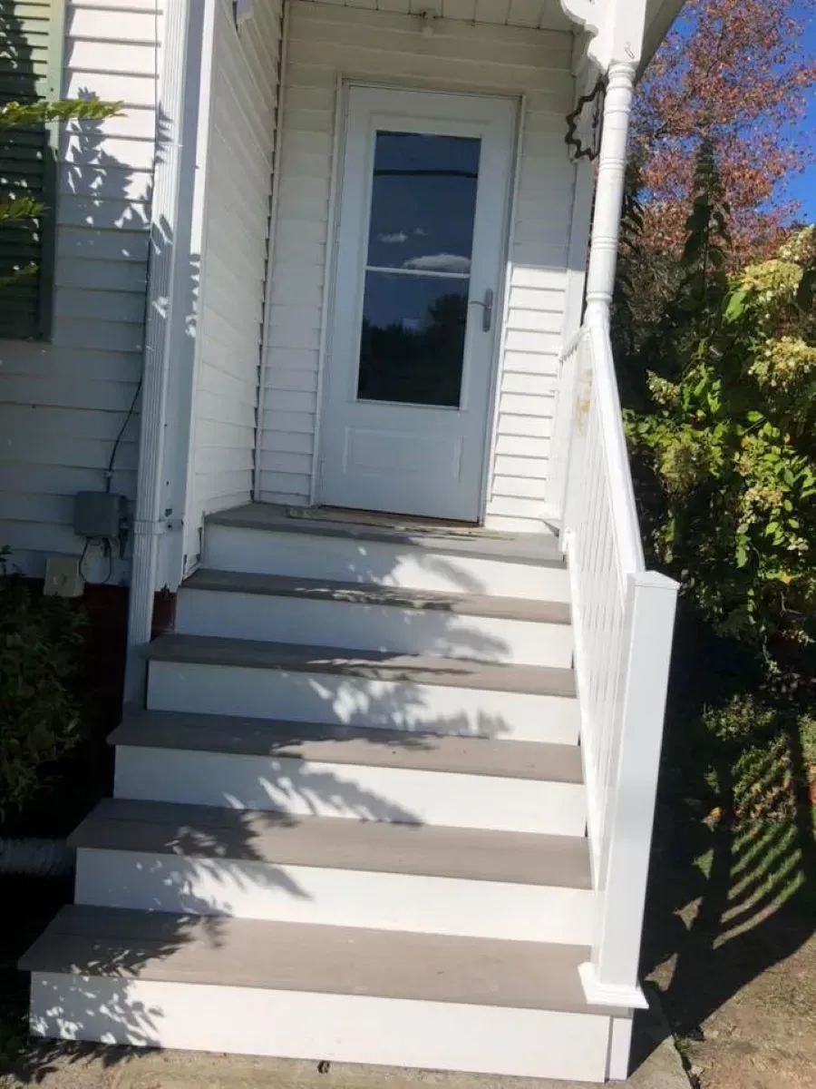A white house with stairs leading up to the front door.