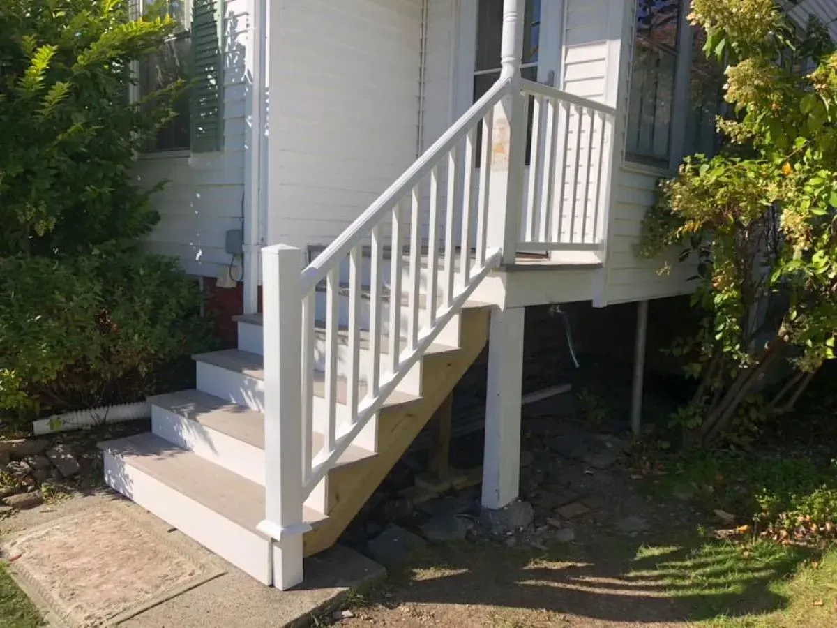 A white house with stairs and a white railing