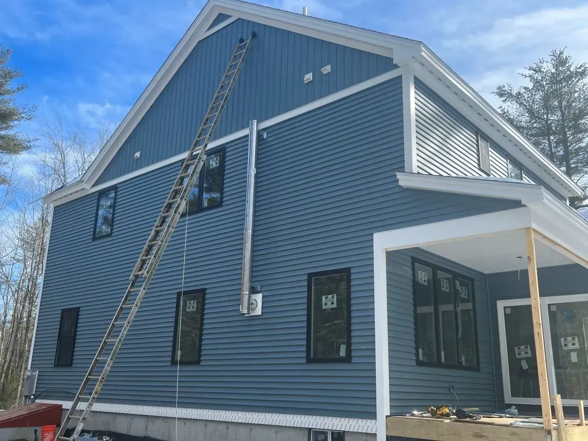 A blue house is being built with a ladder on the side of it.