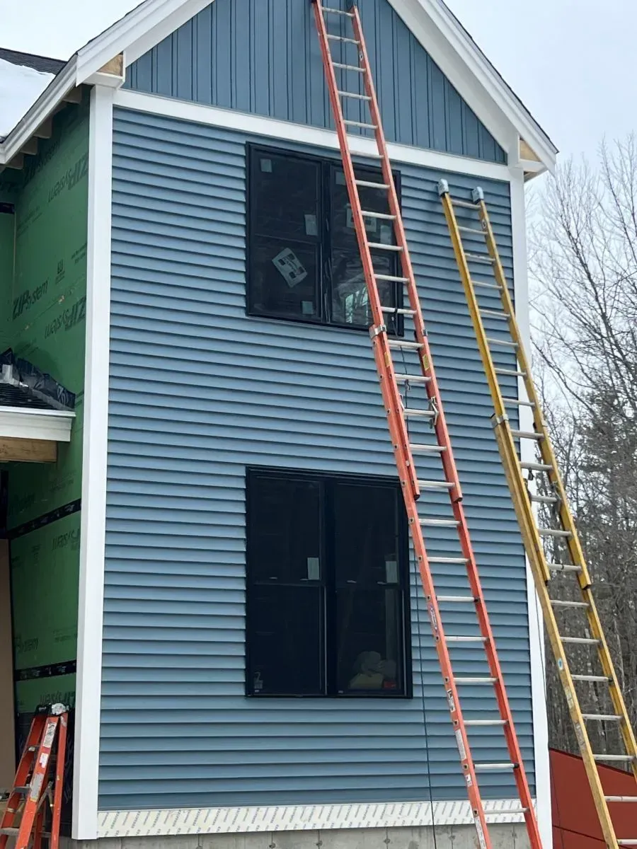 A house is being remodeled and a ladder is sitting on the side of it.