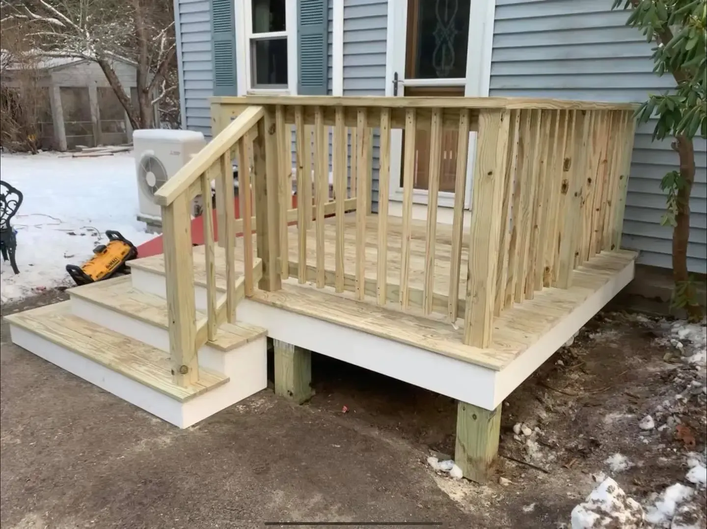 A wooden deck is being built in front of a house