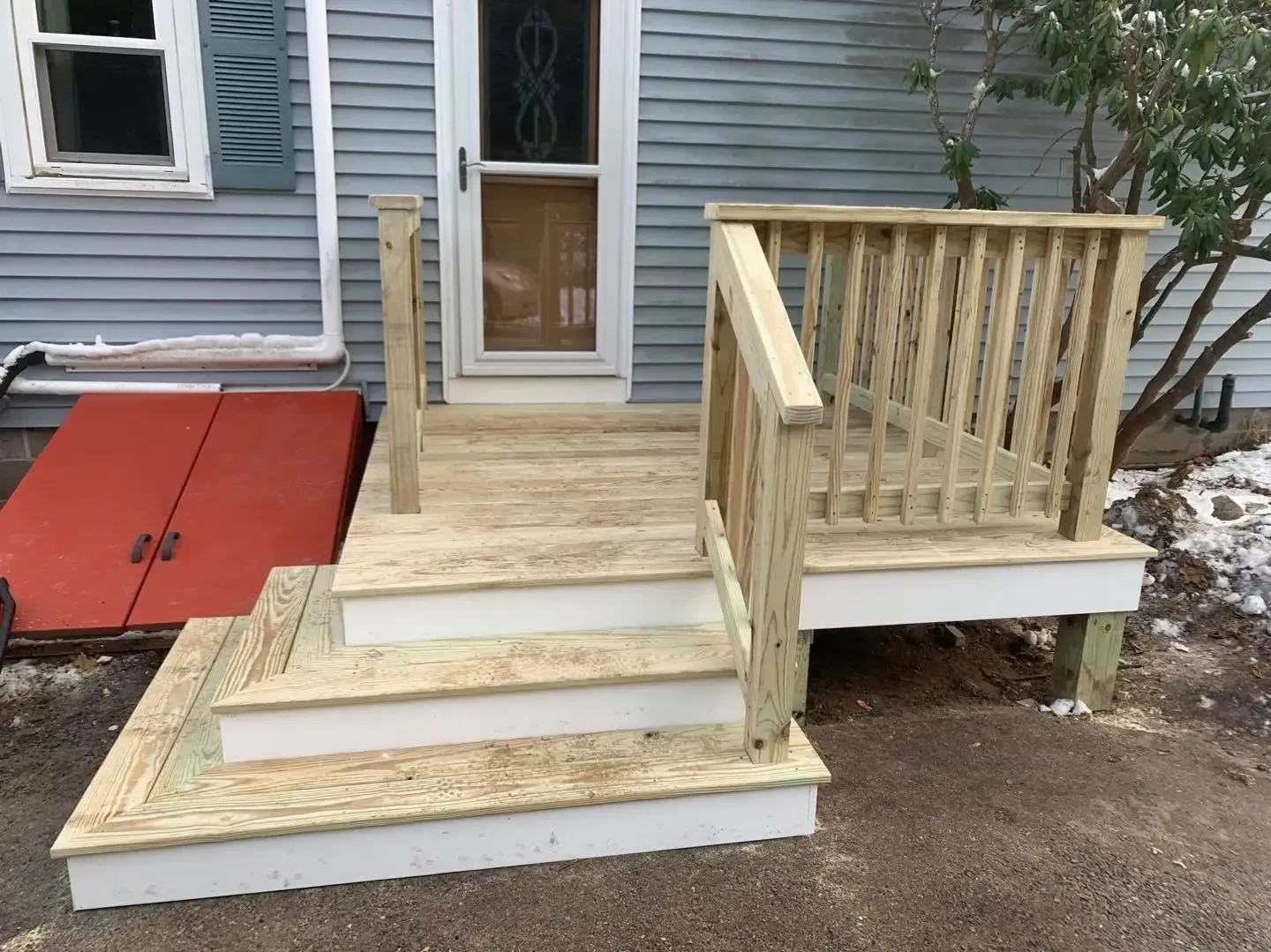 A wooden deck with stairs is in front of a house.