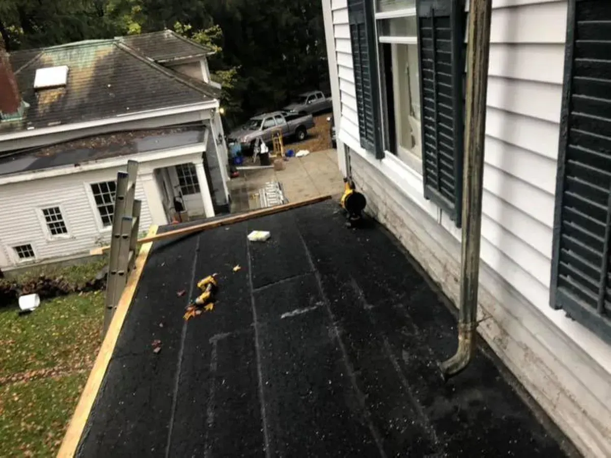 A black roof is being installed on the side of a house.