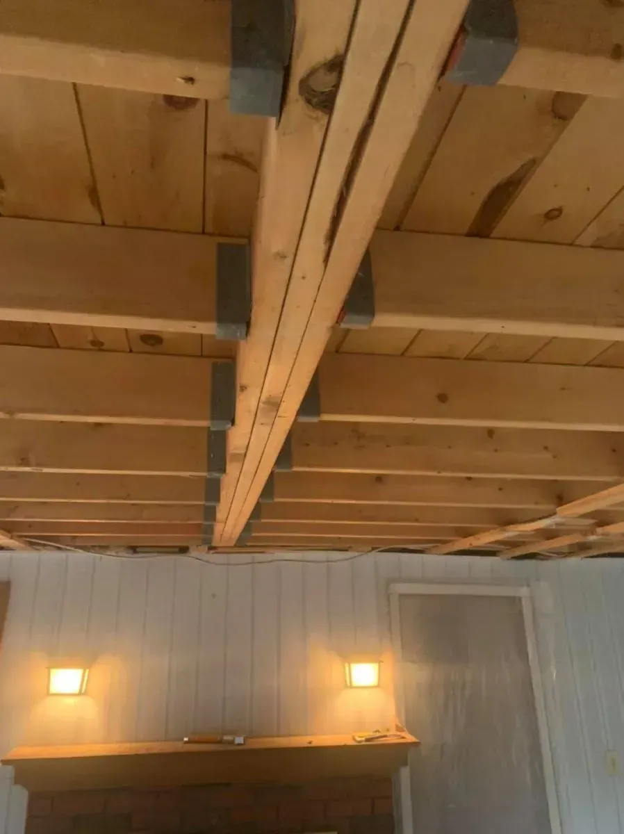 A living room with a wooden ceiling and a fireplace.