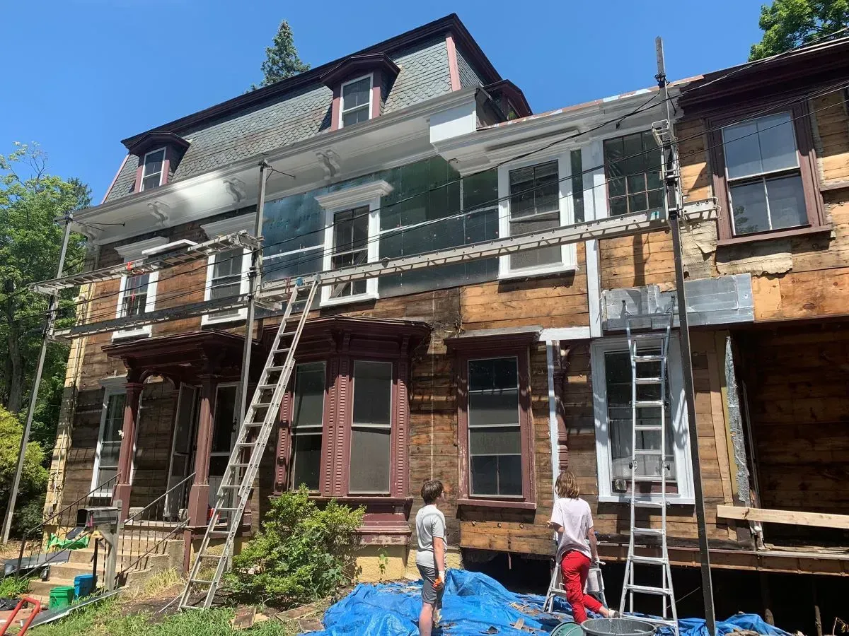 A group of people are working on a large wooden house.