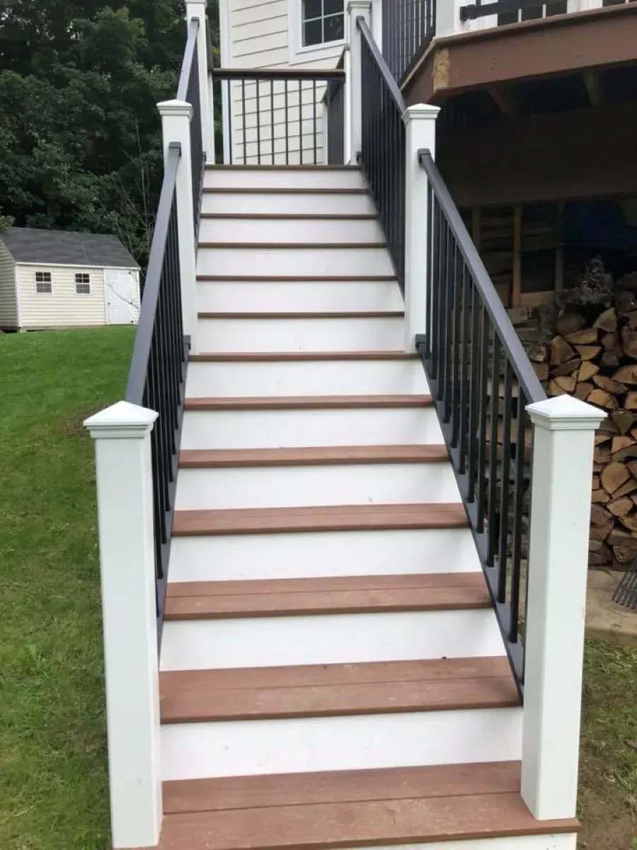 A set of stairs leading up to a deck with a black railing.