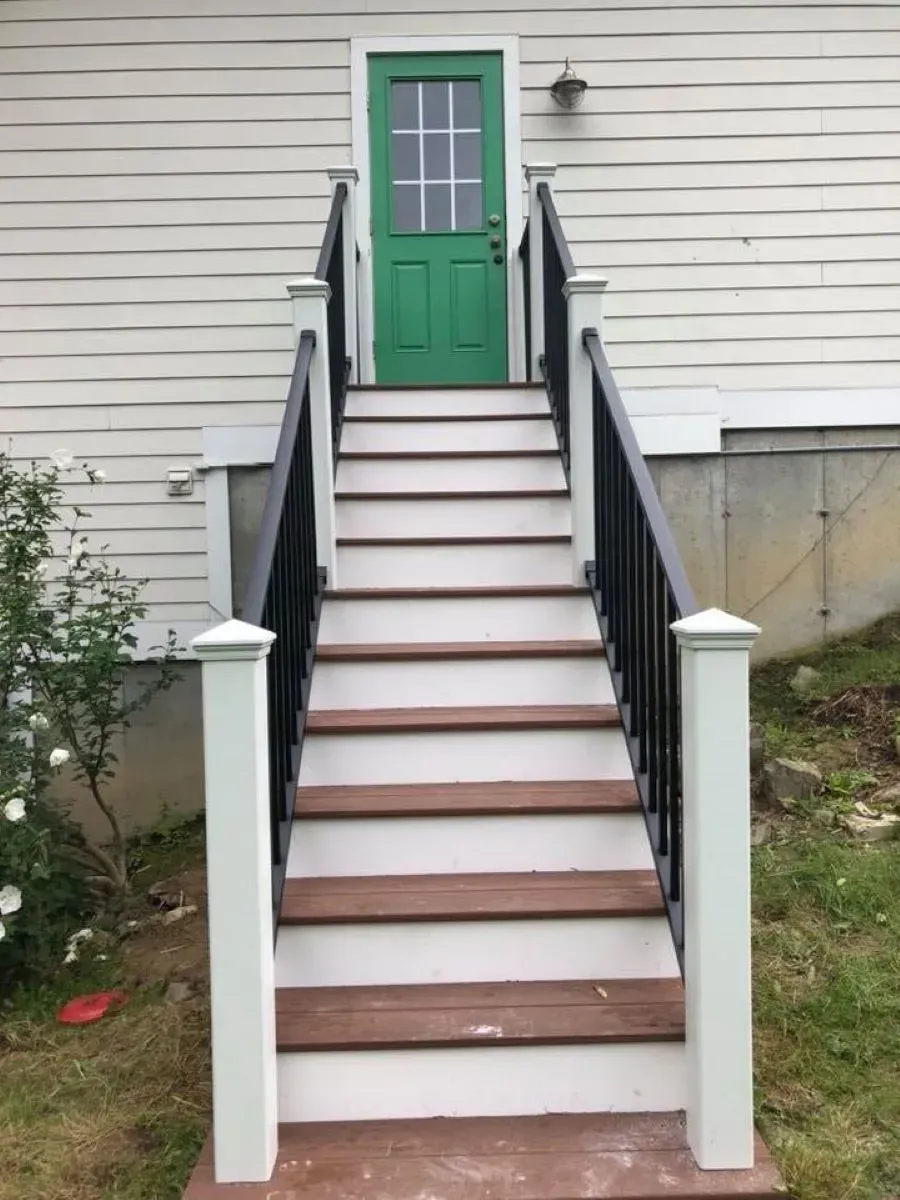 A set of stairs leading up to a green door of a house.