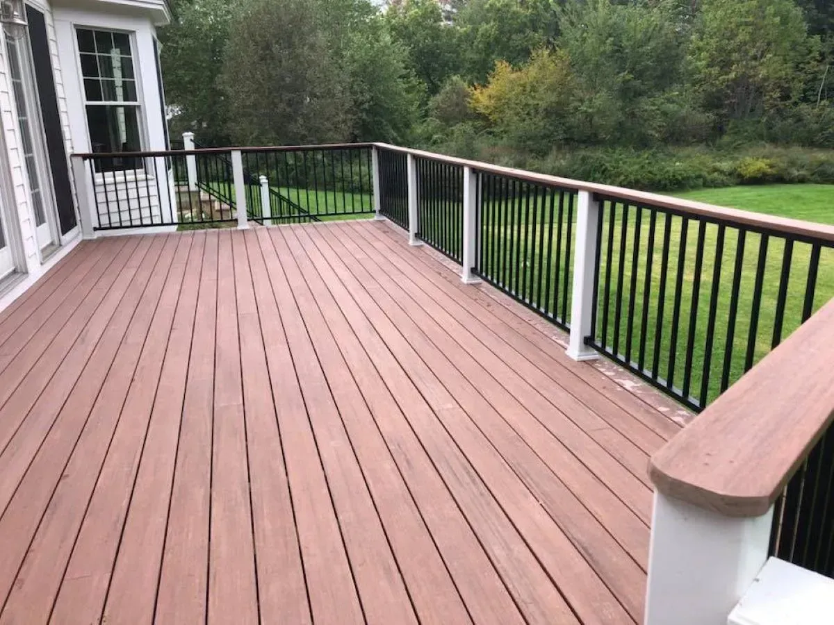 A large wooden deck with a black railing and a white railing
