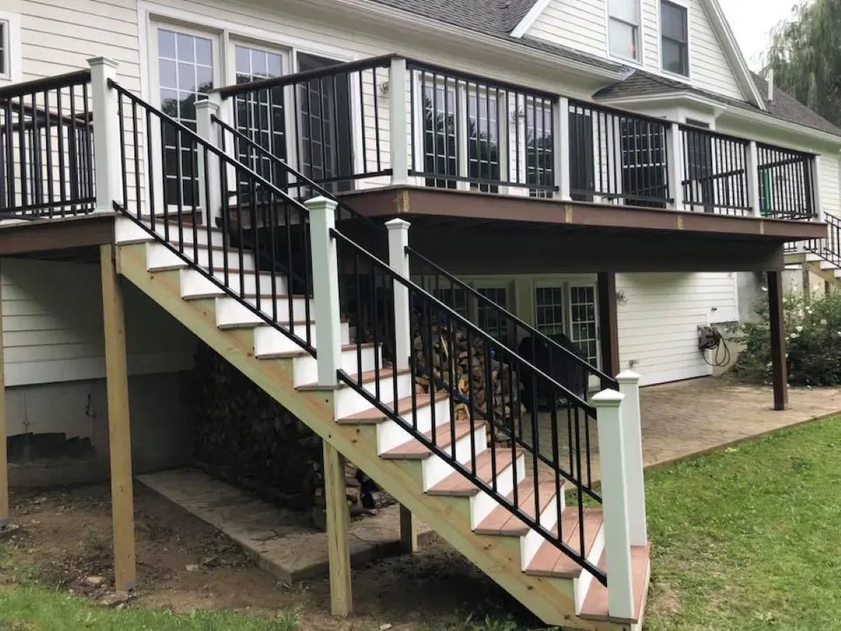 A deck with stairs leading up to it and a house in the background.